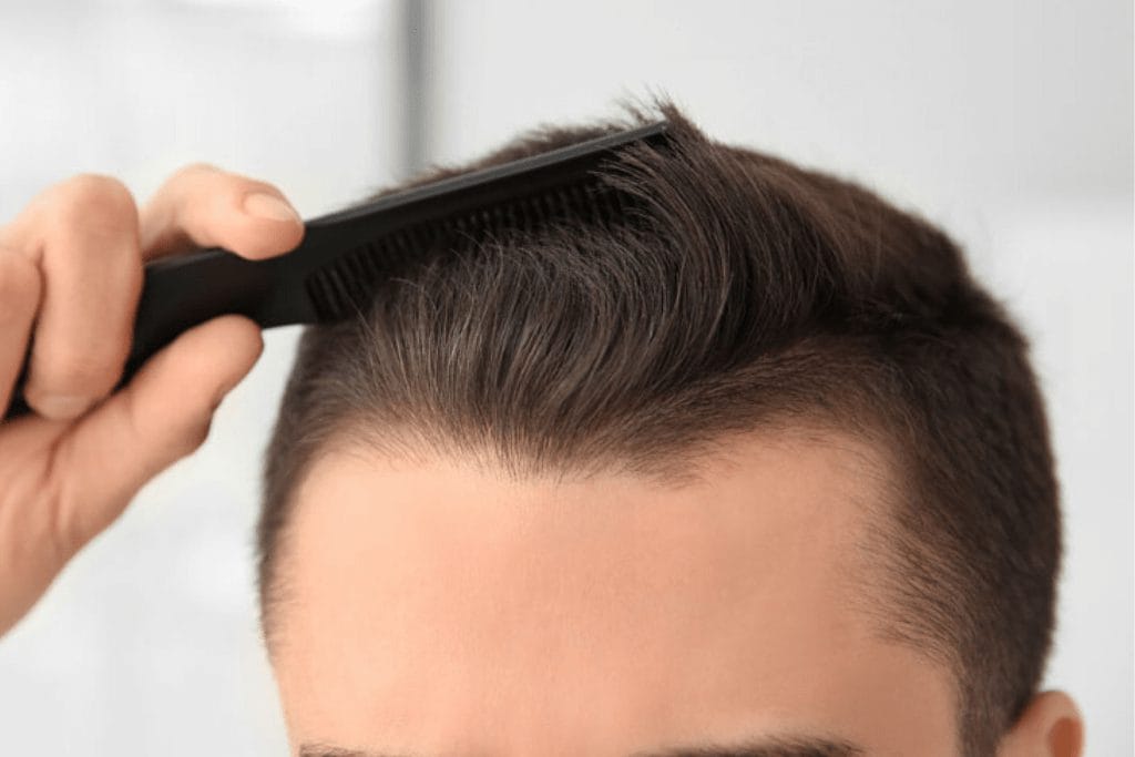 Close-up view of a person combing their hair with a black comb.