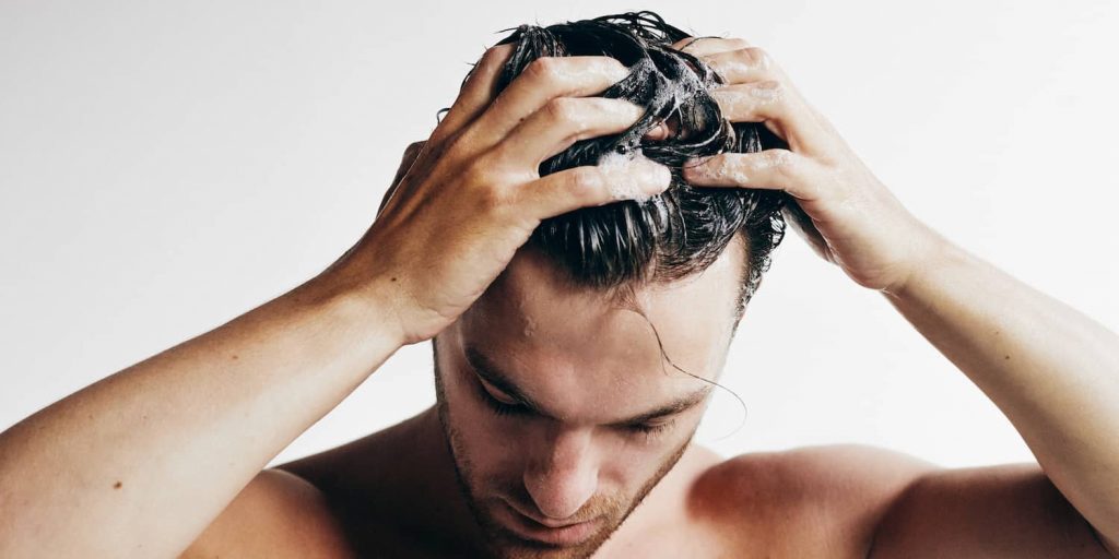 Man carefully washing his hair to protect delicate follicles.
